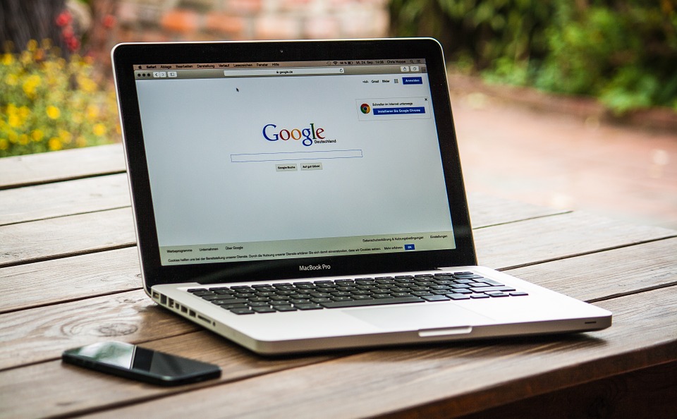 Laptop mit geöffneter Google-Suche auf einem Gartentisch